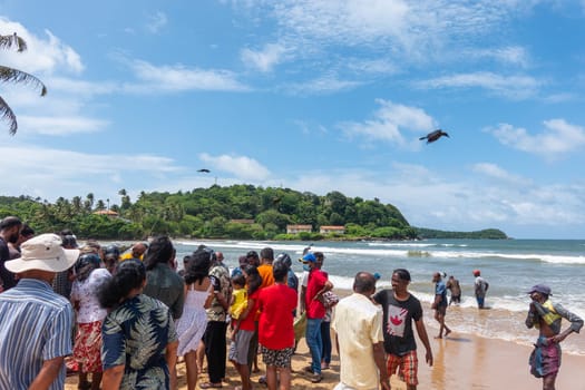 Galle, Sri Lanka - September 14 2024; Tourists gather on beach to watch people of local village chanting while  pulling in a catch of fish while net fishing off of the coast of Galle, Sri Lanka. Net fishing or Ma'a dal fishing is a traditional way of fishing from the shore that can be seen on the western and southern coasts of Sri Lanka.