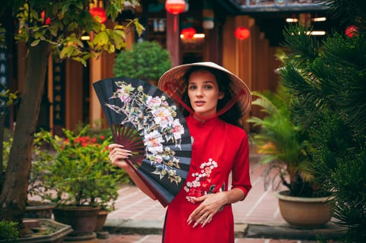 Portrait of a female tourist traveler in a Vietnamese cone hat Non La at the Hoi An pagoda in Vietnam in Asia