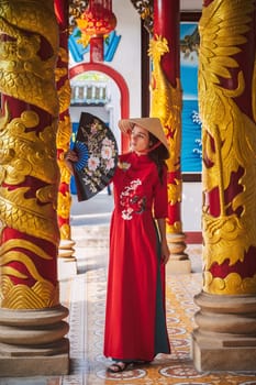young tourist girl in a traditional Vietnamese hat Non La visits the landmark of Buddhist temple in Asia in Vietnam