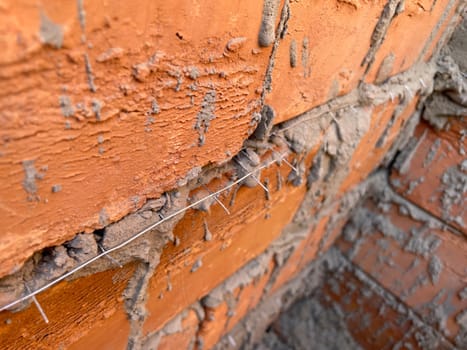 Layered brick masonry with visible horizontal steel reinforcement rods between the rows.