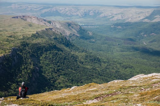 Male tourist looking at landscape green forest from mountain top
