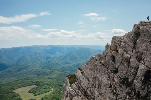 Male tourist looking at landscape green forest from mountain top