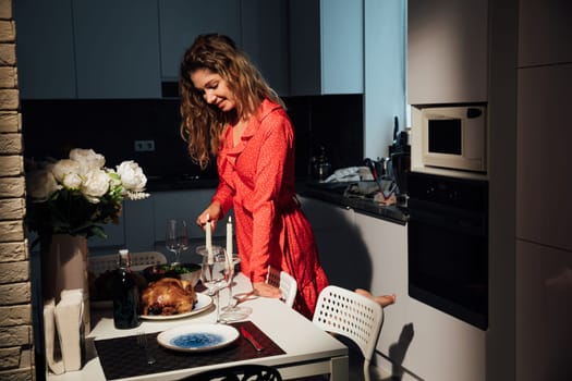 Woman in a red dress cooked food for a romantic evening in the kitchen