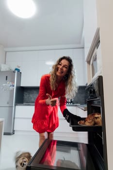 Woman in red dress cooking food in oven in kitchen