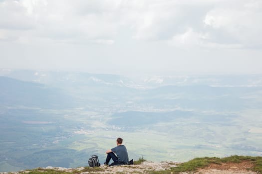 Male tourist looking at the beautiful landscape from the top of the mountain