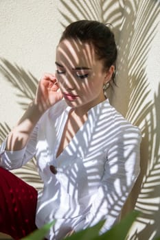 Beautiful gentle brunette woman in summer sitting in the shade of a palm tree