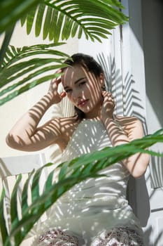 Beautiful gentle brunette woman in summer sitting in the shade of a palm tree