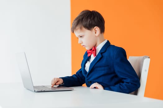 Boy in school uniform working on laptop online