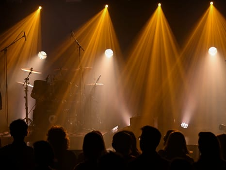 Bright lights illuminate the stage as musicians tune their instruments. A crowd gathers, eagerly anticipating a vibrant concert experience filled with energy and excitement.