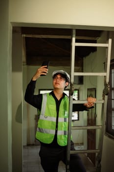 Construction worker standing by ladder, capturing photos of renovation site.