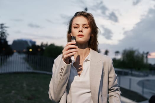Businesswoman standing outdoors at dusk, holding a smartphone, exuding confidence and professionalism. Perfect for business and empowerment themes.