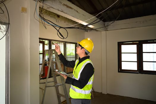 Male construction supervisor examining electrical cables at renovation site.