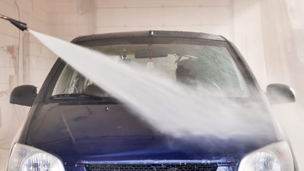 High pressure water jet cleaning car in professional car wash station