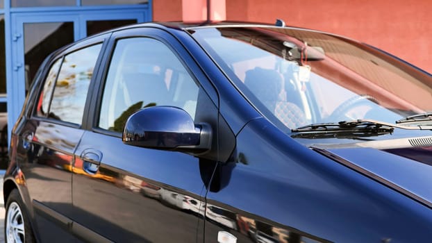 Freshly washed car parked near car wash, reflecting surrounding buildings in its polished surface