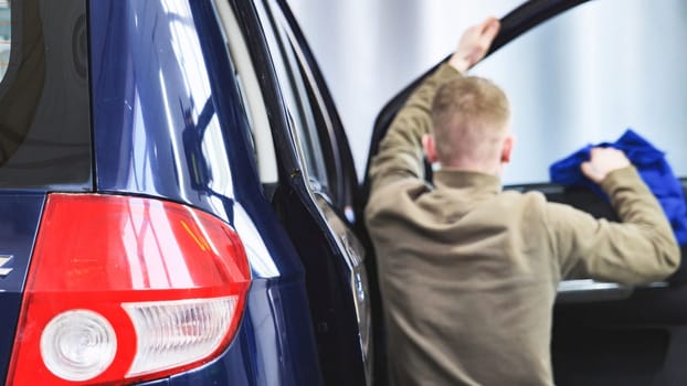 Professional car wash worker cleaning car interior with microfiber cloth, focusing on car detailing and hygiene