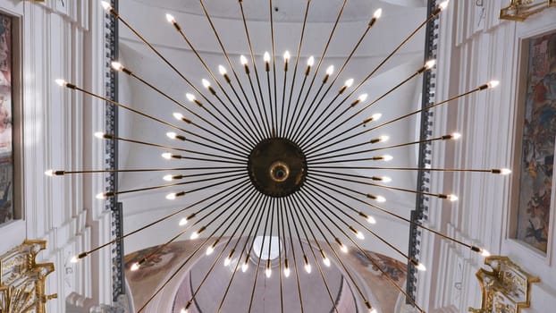 Modern round chandelier hanging from ceiling in church, illuminating interior with warm light