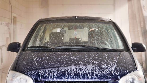A worker coats a car with wax after washing the car