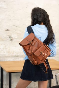A fashionable model confidently showcasing a modern outfit while sporting a brown backpack accessory