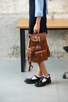 A fashionable model confidently showcasing a modern outfit while sporting a brown backpack accessory