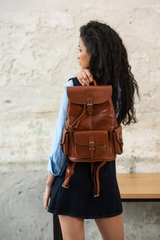 A fashionable model confidently showcasing a modern outfit while sporting a brown backpack accessory