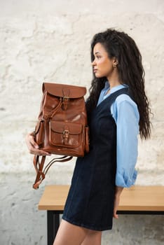 A fashionable model confidently showcasing a modern outfit while sporting a brown backpack accessory