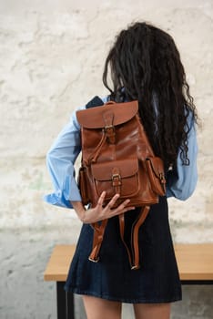 A fashionable model confidently showcasing a modern outfit while sporting a brown backpack accessory