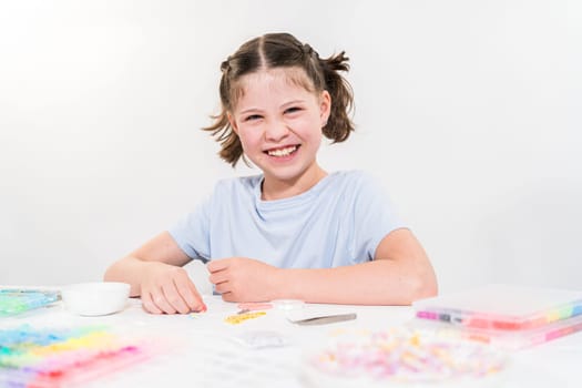 Little girl enjoys crafting colorful bracelets with vibrant clay beads set.