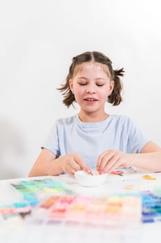 Little girl enjoys crafting colorful bracelets with vibrant clay beads set.