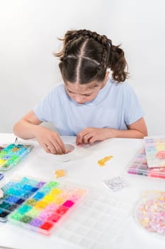 Little girl enjoys crafting colorful bracelets with vibrant clay beads set.