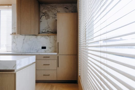 A beautifully designed kitchen featuring elegant wooden cabinets, a spacious refrigerator, a functional sink, and a window adorned with stylish blinds