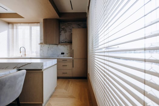 This is a kitchen that features elegant blinds adorning the windows and a stunning marble countertop that adds to its beauty