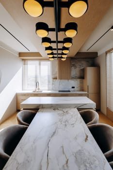 A beautifully designed kitchen features a stunning marble table, complemented by elegant chairs, along with a charming chandelier gracefully hanging from the ceiling