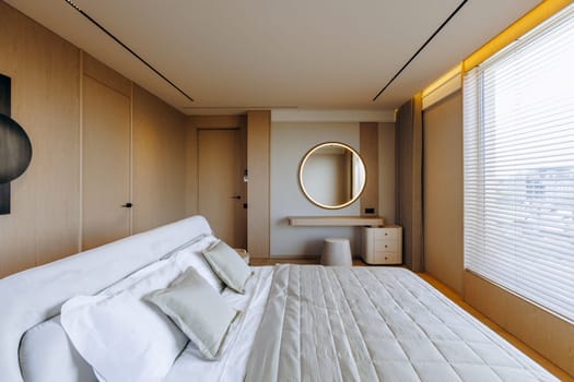 In a bedroom, there is a spacious large bed beautifully arranged, complemented by an elegant mirror mounted on the wall beside it