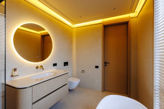 This is a bathroom equipped with essential features including a sink, toilet, mirror, and a comfortable bathtub for relaxation