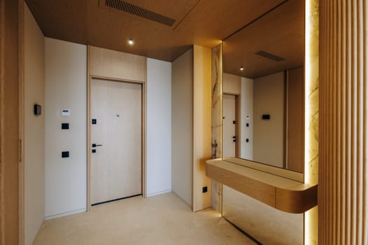 A narrow hallway featuring a sleek mirror mounted on the wall along with a sturdy door leading to another room nearby