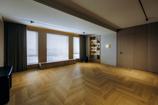 A stylish contemporary living area that boasts large windows, beautiful hardwood flooring, and minimalist decor style