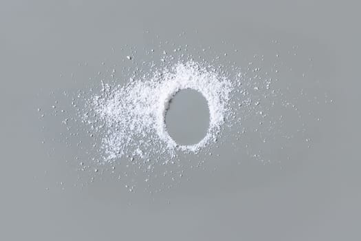 Scattered white powder on grey with copy space in middle top view. Baking soda or medical powder. Preventive medicine and healthcare, taking alternative dietary supplements. Kitchen spices