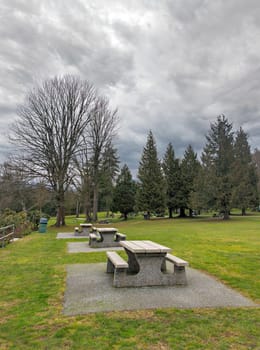 Picnic tables and benches on green lawn in a park on winter season in British Columbia