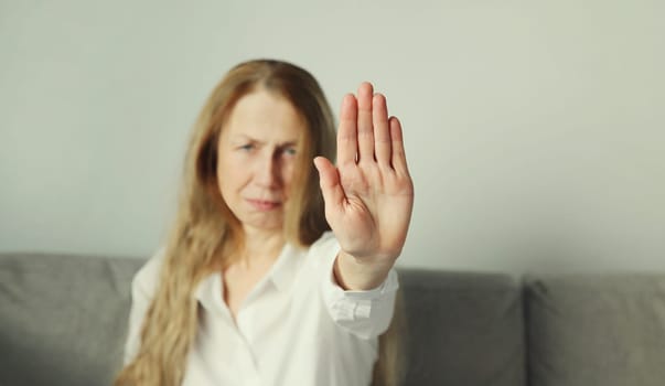 Close-up upset woman shows stop, no or enough sign with palm of hand, refusal gesture, domestic violence