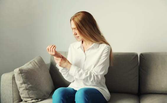 Unhealthy young woman suffers from wrist pain, tunnel syndrome due to working on the computer for a long time, unwell girl touching her hand. Neuralgia and injuries concept
