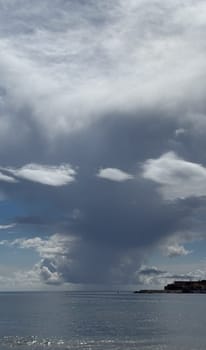 The dramatic formation of clouds over the serene seascape highlights the beauty and tranquility of nature.