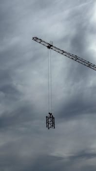 Budva, Montenegro - April 18, 2025: Construction crane hoisting materials against a backdrop of a dramatic sky, symbolizing the essence of building and development
