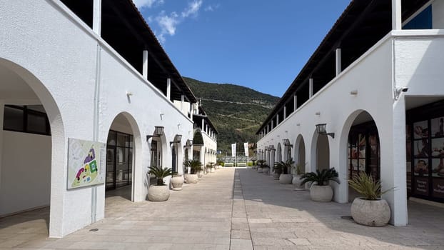 Budva, Montenegro - April 17, 2025: the street between the snow-white arches of the Hotel Aleksandar with mountain views
