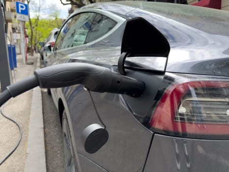 Electric vehicle recharging at public urban station, symbolizing eco friendly transport solutions, clean energy usage and the shift toward sustainable city infrastructure