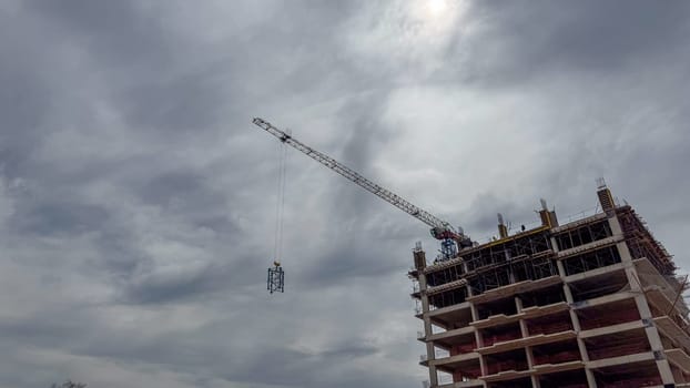 Budva, Montenegro - April 18, 2025: Swissotel's construction site, featuring a crane lifting materials against a cloudy sky, highlights the city's development and architectural progress