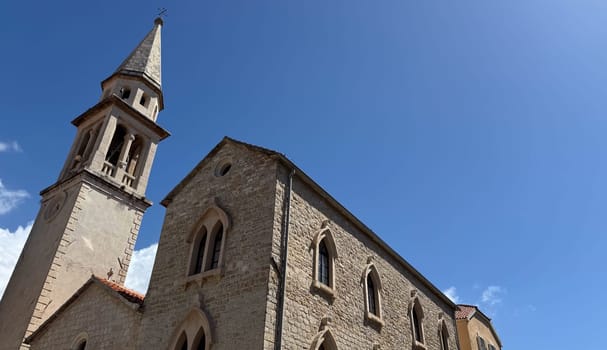 Budva, Montenegro - April 20, 2025: Historic Church of St. John the Baptist, with a blue sky in the background