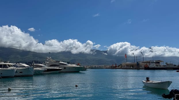 Budva, Montenegro - April 18, 2025: A view of the harbor with yachts and boats against the background of blue skies and clouds, embodying coastal relaxation and tranquility