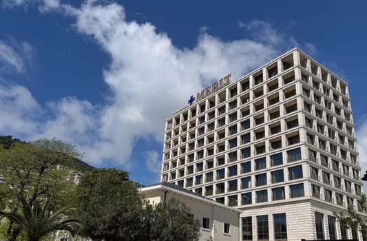 Budva, Montenegro - April 18, 2025: The modern architecture of the Merit Hotel rises in a picturesque setting under a blue sky with clouds