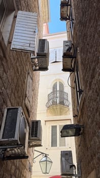 Budva, Montenegro - April 18, 2025: Urban architecture, air conditioning in a narrow alley, unique design elements of history and elements of modern urban life.