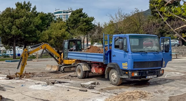 Budva, Montenegro - April 18, 2025: Construction equipment is actively working at the construction site: a blue truck and an excavator for efficient work